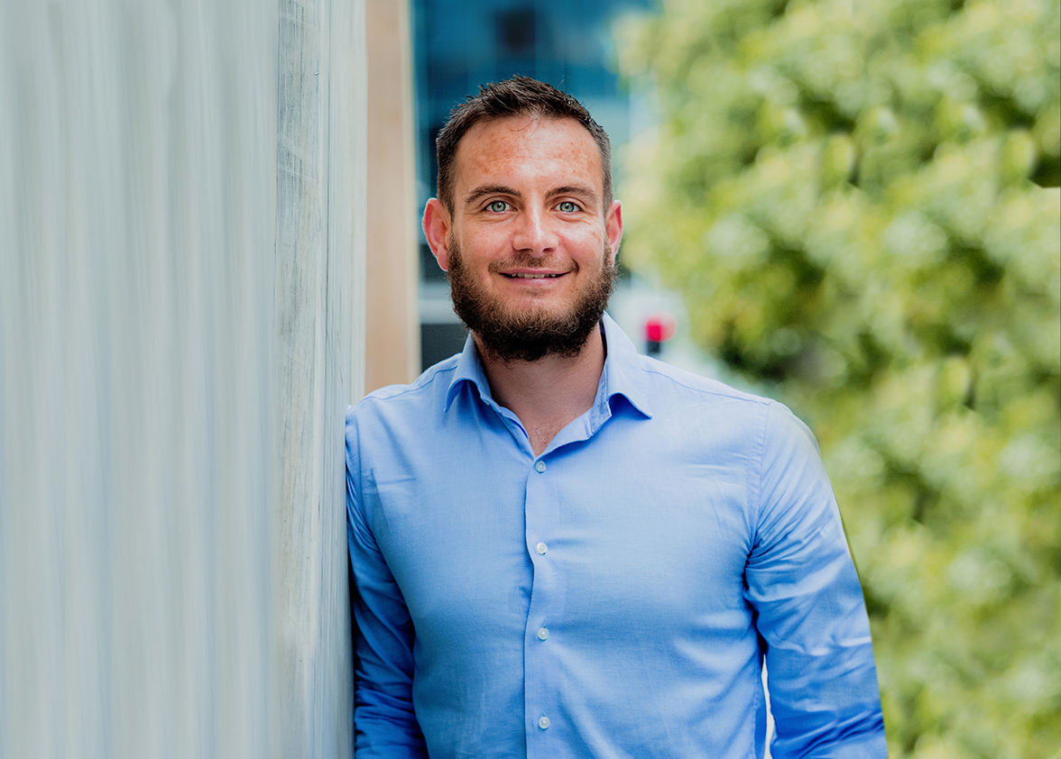 a corporate headshot portrait of civil structural design man engineer russel odendaal in front of trees against a wall